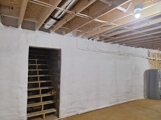 A basement with brick walls, insulated with closed cell spray foam. The foam was applied to the walls and the rim joists.