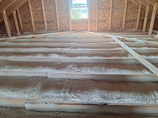 An attic floor insulated and air-sealed with closed cell spray foam insulation.