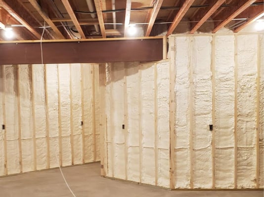 A basement wall insulated with closed cell spray foam insulation.