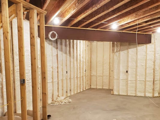 A basement insulated with closed cell spray foam. A wood-frame wall is constructed in front of the masonry walls so the basement can be finished.
