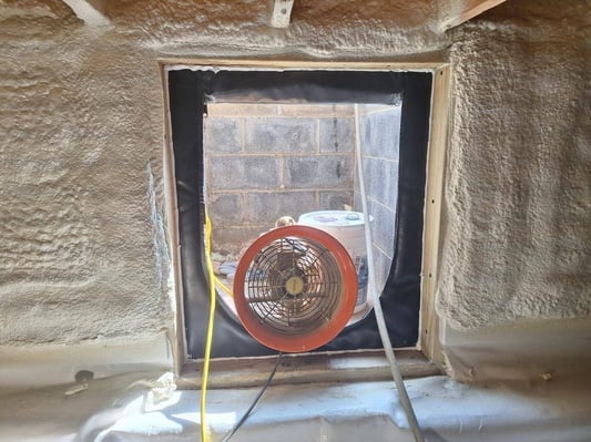 Ventilation set up in a crawl space during its encapsulation, which involved installing closed cell spray foam insulation on the walls.