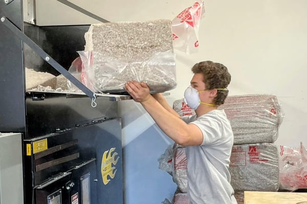 An insulation crew member loading cellulose insulation into a professional system.