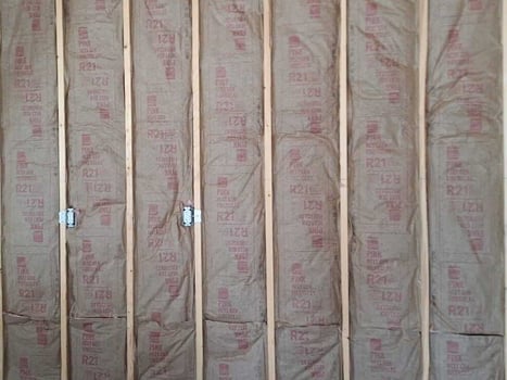 Fiberglass batt insulation with vapor retarder facing installed in a wood framed wall.