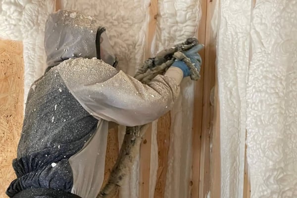 A spray foam insulation contractor installing open cell spray foam in the exterior walls of a new construction home.