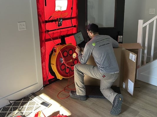 A technician from South Central Services completing a blower door test on a new construction home.