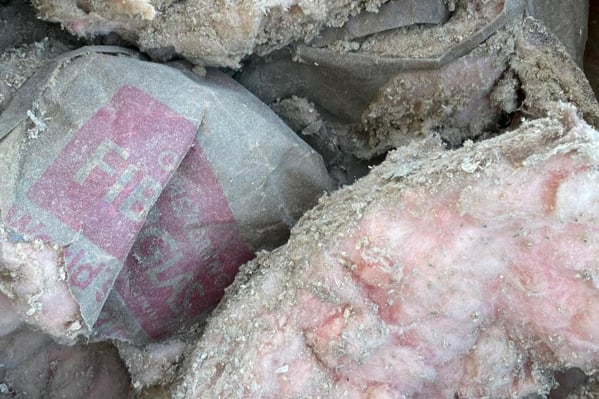 Insulation removed from an attic: fiberglass batts coated in cellulose dust.