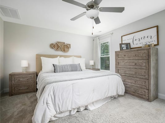 A bedroom with a carpeted floor and a ceiling fan.