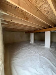 An encapsulated crawl space with wrapped pillars, closed cell spray foam, thick plastic sheathing, and an empty ceiling.