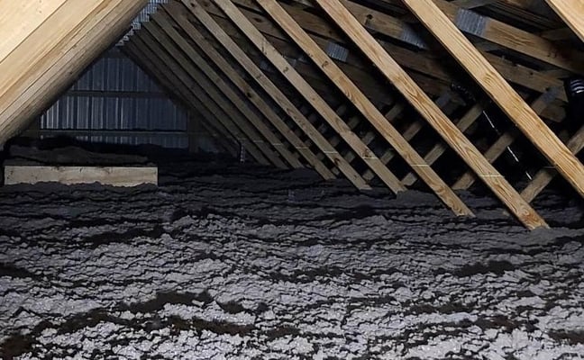 An attic floor insulated with blown-in cellulose insulation.