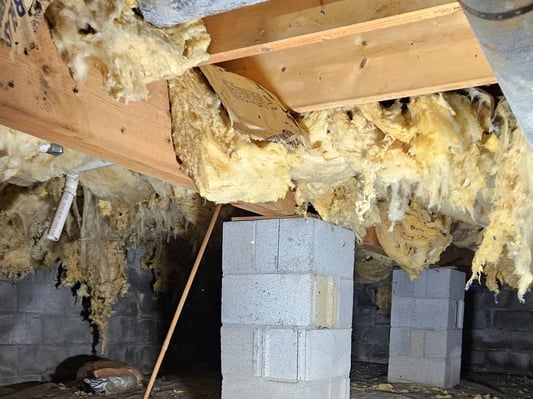 Batt insulation falling out of the ceiling of a crawl space.