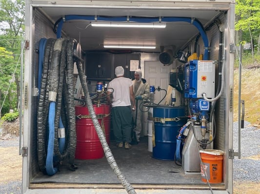 Two spray foam crew members inside of a spray foam insulation rig.