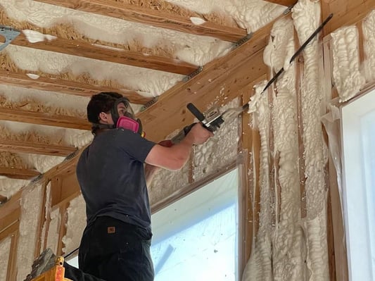 A spray foam insulation crew member trimming excess open cell spray foam from wall cavities in a new construction home. Located in Fayetteville, PA.