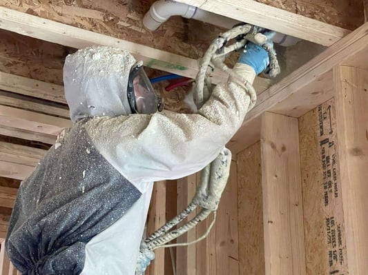 A spray foam insulation contractor installing open cell spray foam in a new construction wood cavity.