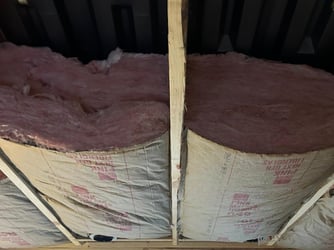 Fiberglass batt insulation installed in a basement ceiling.