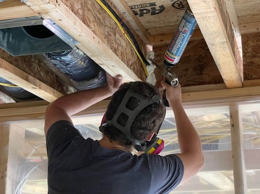 A spray foam insulation crew member installing professional can foam as an air-sealing product.