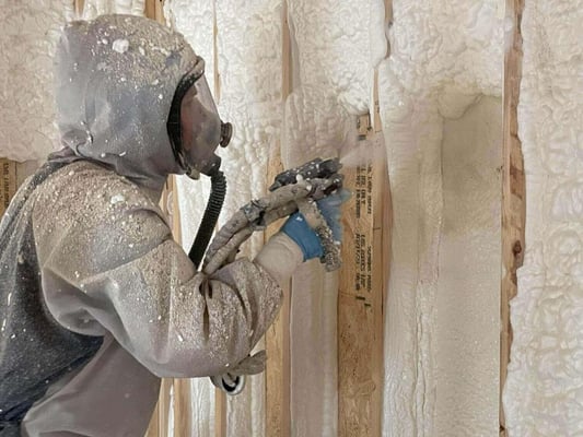 A spray foam contractor installing open cell spray foam into a wood new construction wall.