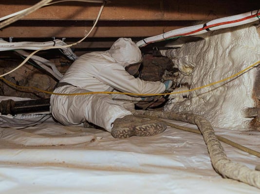 A spray foam contractor installing closed cell spray foam on the irregular stone walls of a crawl space in Chambersburg, Pennsylvania.