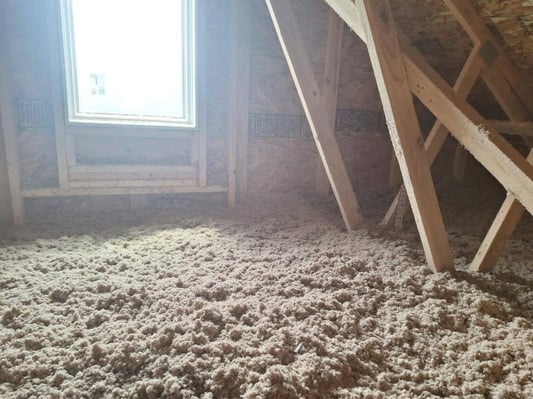 An attic with blown-in cellulose insulation on the attic floor.