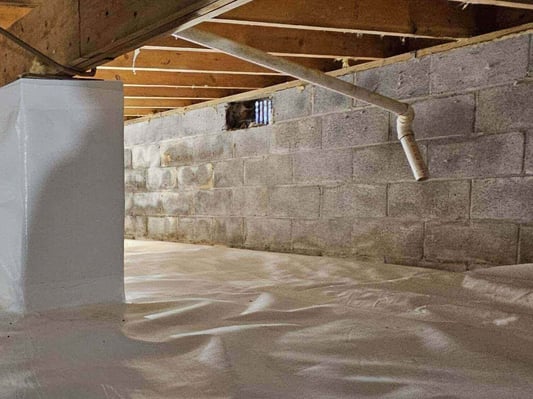 A crawl space mid-encapsulation. The vapor barrier has been installed on the floor and the pillars have been wrapped. The walls are not yet insulated.