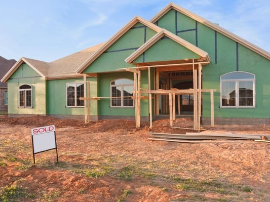 A new construction home with a "sold" sign in the front of the lot.