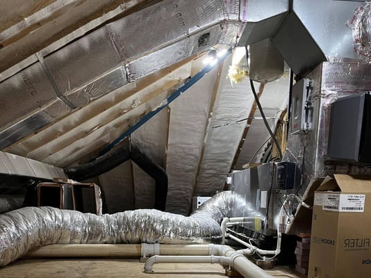 An encapsulated attic with closed cell spray foam on the ceiling. The attic includes HVAC equipment and ductwork.