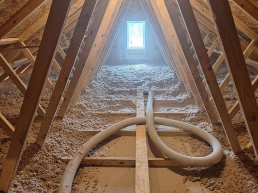 An attic being professionally insulated with blown-in cellulose.