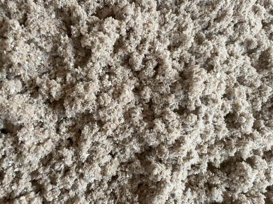 A close-up of loose-fill cellulose insulation after being broken down to blown-in insulation consistency.