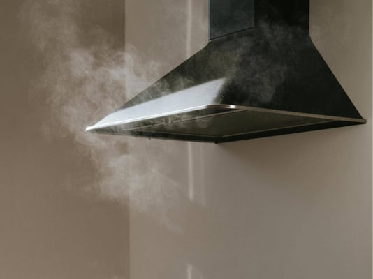 A kitchen range hood with steam rising nearby.