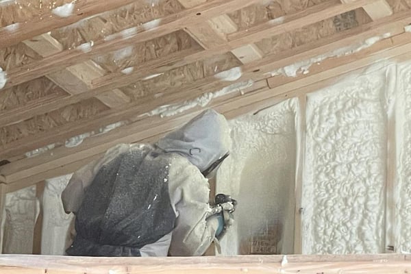 A professional spray foam contractor installing open cell spay foam insulation to a wood new construction substrate.