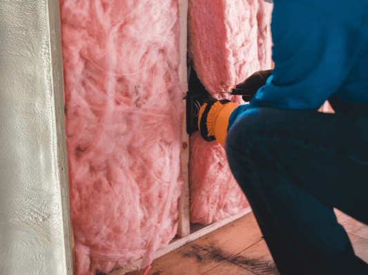 An insulation contractor installing traditional flash and batt insulation.