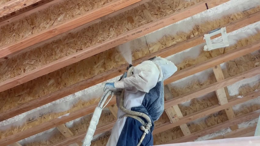 Contractor installing open cell spray foam in a loft.
