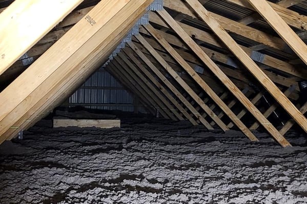 A vented attic floor insulated with blown-in cellulose.