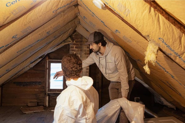 Two crew members at South Central Services removing insulation from an attic in downtown Chambersburg, PA.