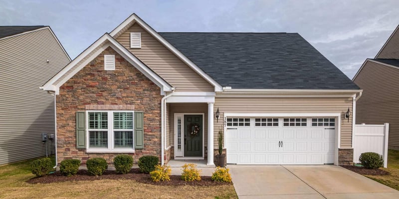 A one-story home, located in a development, with a garage and minimal landscaping.