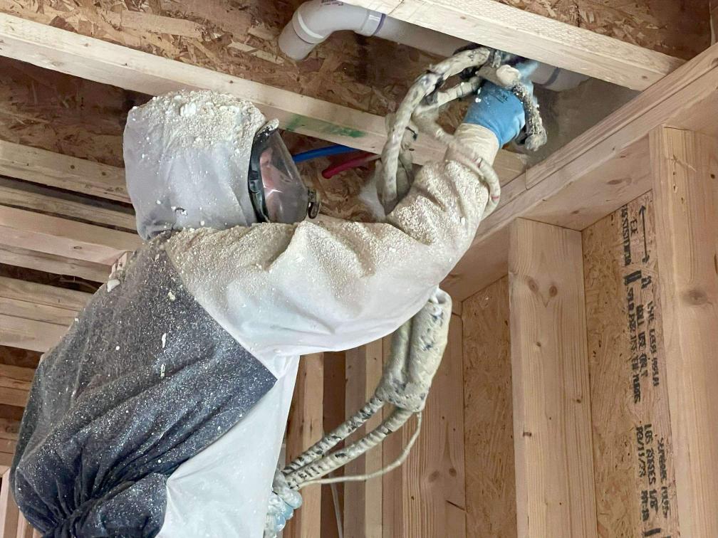 A spray foam insulation contractor insulating a new construction home with open cell spray foam.