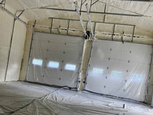 The garage doors of a pole building, covered with plastic to protect from overspray.