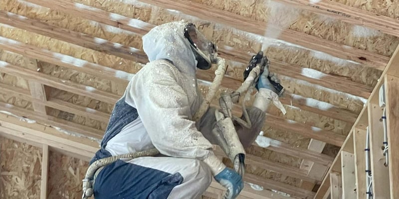 A spray foam insulation contractor insulating a ceiling with open cell spray foam.