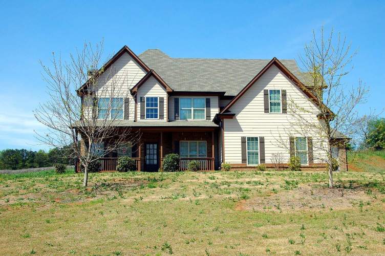 A two story house with trees and bushes in the front yard.